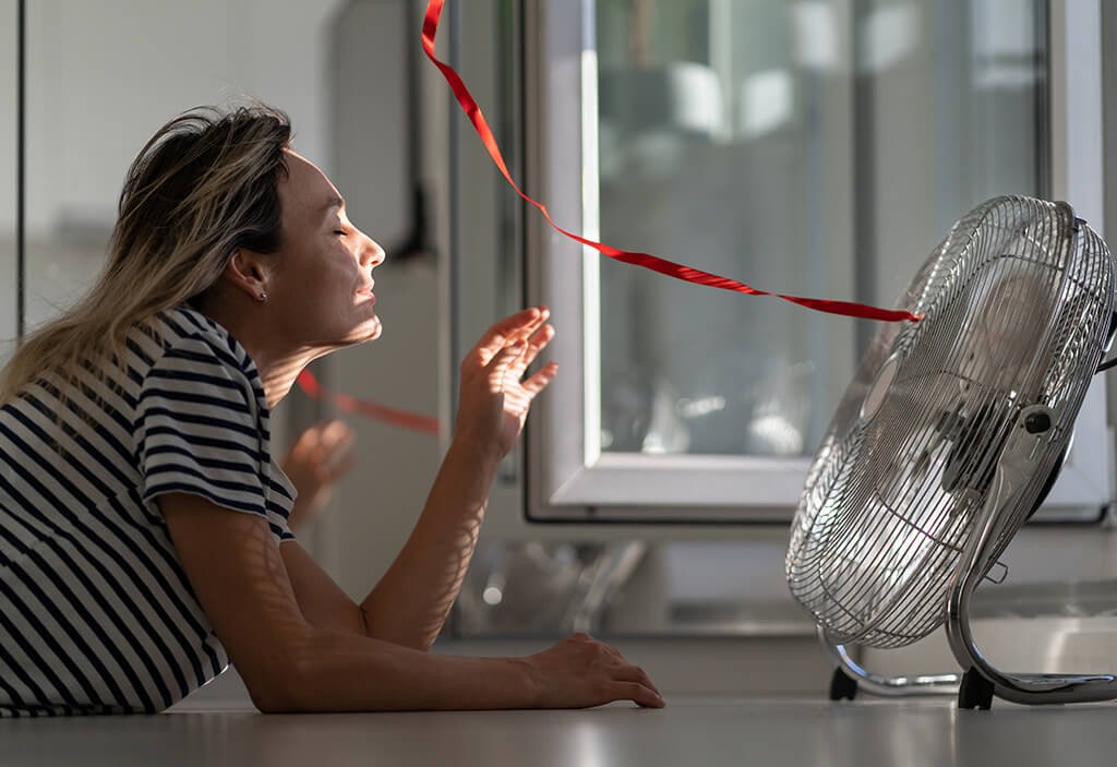 Women Cooling Herself in Front of Desktop Fan - Best Air Conditioner on the Market