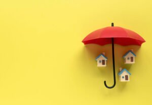 Apartment Safety Tips - Image of an Umbrella open over 3 toys house to symbolize an umbrella policy in insurance